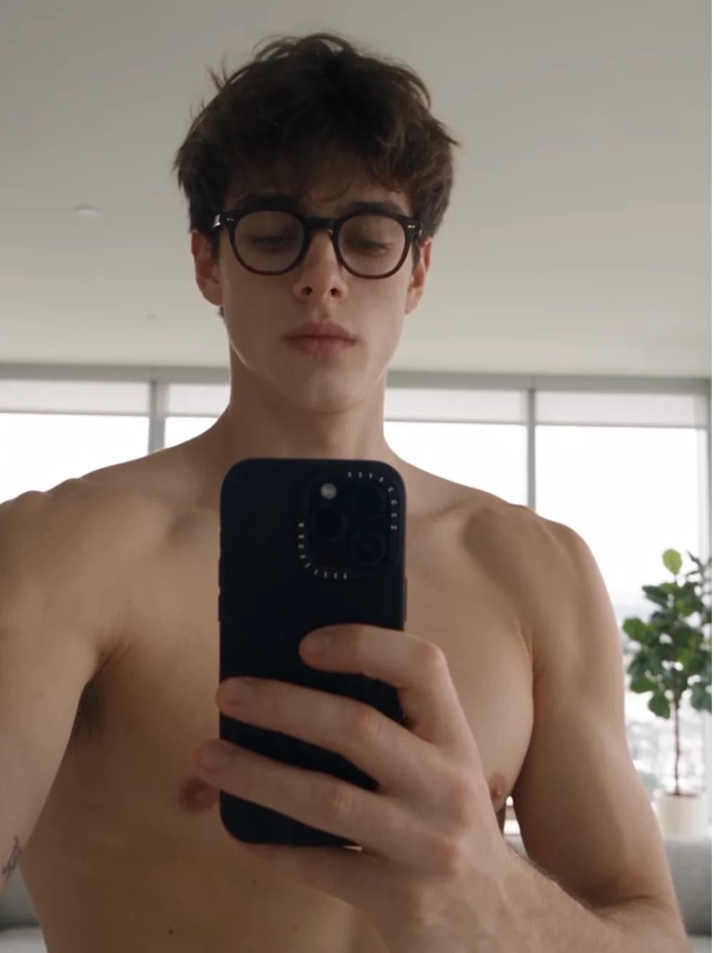 Rick wearing glasses, taking a mirror selfie in a bright room
